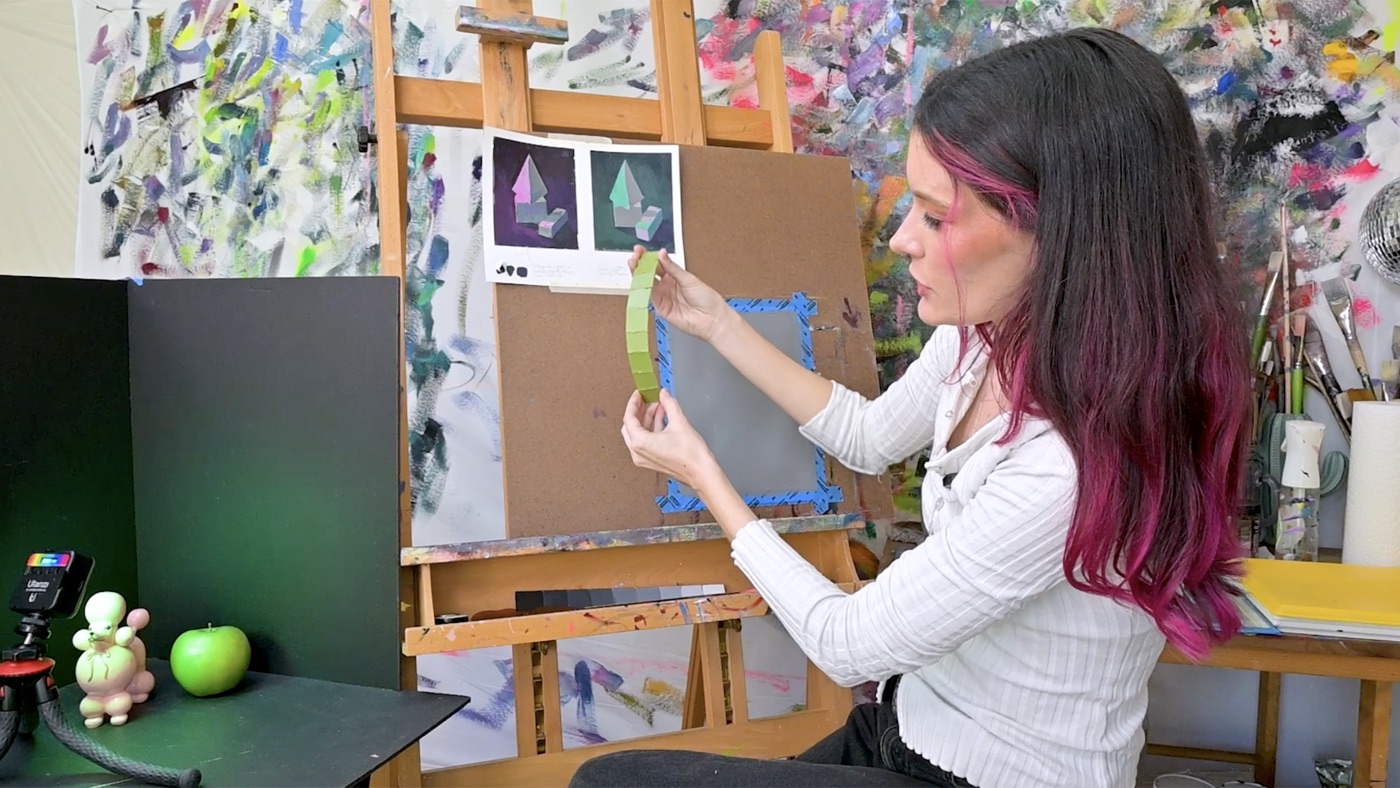 Sari Shryack demonstrating a value study, holding a painted color gradient next to a reference sketch